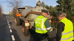 Un guardia civil de Tr�fico examina la documentaci�n de un tractor en una carretera gallega