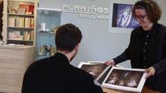 Un padre, consultando un lbum de fotografas de primeras comuniones en una tienda de Lugo.