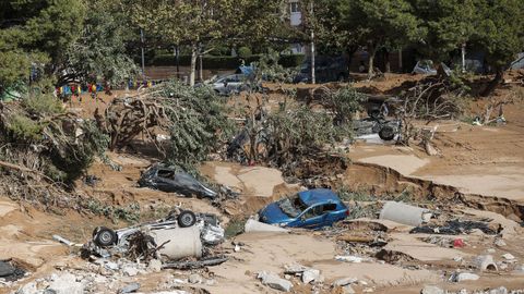 Varios vehculos permanecen semienterrados entre el lodo tras el paso de la dana en Paiporta