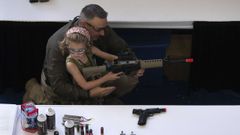 Un hombre muestra a una ni�a c�mo sostener un arma durante la convenci�n anual de la Asociaci�n Nacional del Rifle del 2013, en Houston