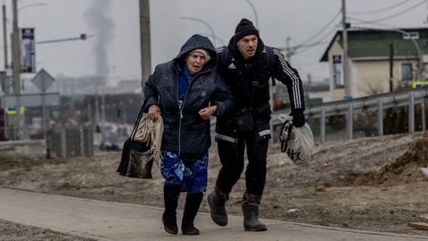 Un hombre ayuda a una anciana a escapar de la ciudad de Irpin 