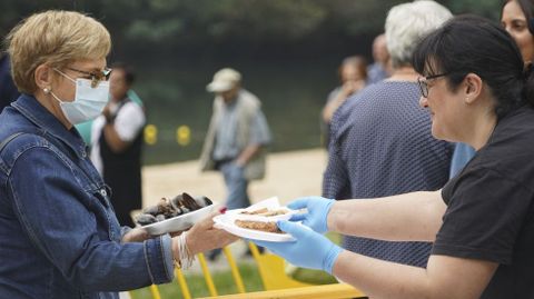 Reparto de raciones de mejillones y empanadas en las inmediaciones de la playa fluvial