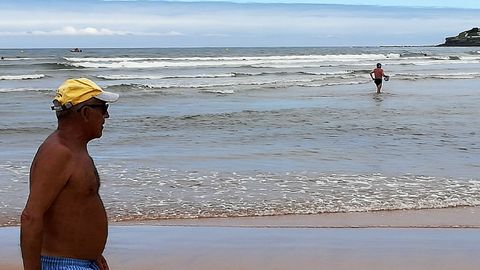 Un paseante y un ba�ista en la apertura de la temporada oficial de ba�os en la playa de San Lorenzo