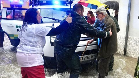 Vecinos de Grazalema ayuda a una persona mayor en una calle inundada 