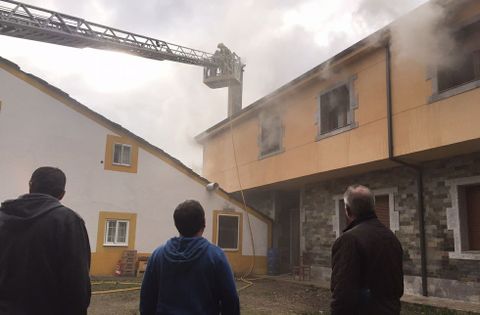 Los vecinos de la zona observando la situación y los bomberos apagando el incendio.