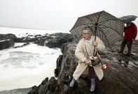 Una muller lanza uns caraveis ao mar desde as pedras das Furnas na homenaxe a Sampedro<span lang= es-es >. </span>