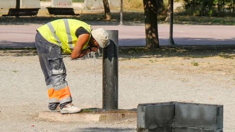 Un operario se refresca en una fuente por las altas temperaturas en un parque de L�rida.