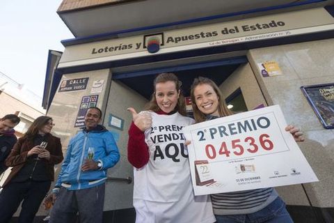 La due�a de la Administraci�n de Loter�a N� 25 de Beniaj�n, Elena Turp�n, acompa�ada de la vendedora Mar�a Garc�a, posan con un cartel que anucia la venta del segundo premio del sorteo de Navidad, el n�mero 04.536