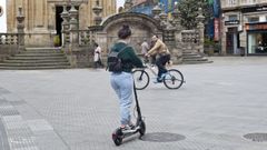 Una usuaria de VMP y un ciclista circulando por la plaza de A Peregrina, zona de convivencia en la que el uso de estos vehículos está permitido