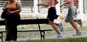 Dos j�venes pasan corriendo junto a una mujer con problemas de sobrepeso, que fuma y bebe un refresco azucarado.