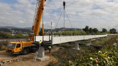 Operarios, este jueves, trabajando en la colocaci&oacute;n de la pasarela en la senda peatonal de la carretera vieja de Mar&iacute;n, la PO-546