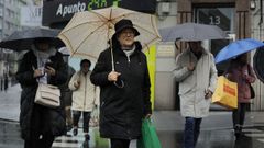 Varias personas cubrindose de la lluvia en A Corua.