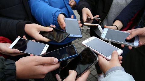 UN GRUPO DE ADOLESCENTES MOSTRANDO SUS TELEFONOS M�VILES