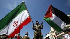 Un militar iraní ondea las banderas de su país y la de Palestina.