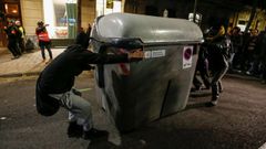 Varios manifestantes mueven un contenedor para utilizarlo de barricada, ayer en Barcelona