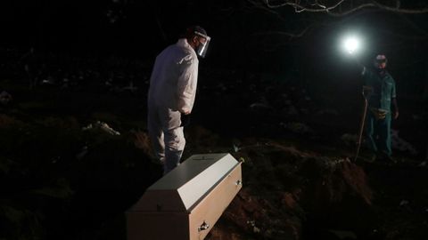 Un sepulturero se prepara para enterrar el cuerpo de una fallecida por covid-19