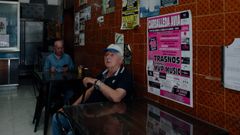 Un vecino de Ribadavia espera un caf� junto a un cartel de las fiestas de Carballeda de Avia.