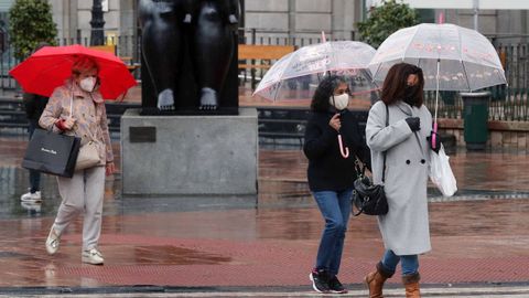 Varias mujeres se protegen de la lluvia con paraguas mientras pasean por una c�ntrica calle de Oviedo