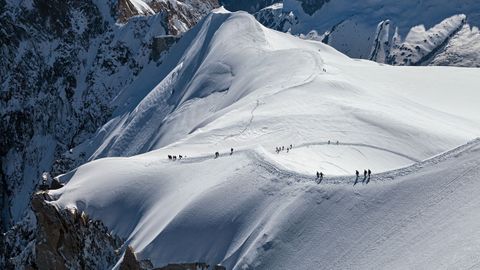 Una serie de escaladores cruzan una creta nevada del Mont Blanc.