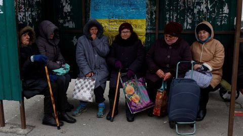 Un grupo de mujeres esperan el autob�s tras recoger ayuda humanitaria en Jers�n.