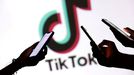 Adolescentes, consultando sus m�viles con el logo de TikTok de fondo.