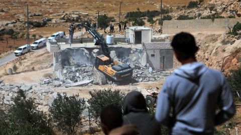 Palestinos observan la demolición de una vivienda en la aldea de Yatta, en el sur de Cisjordania