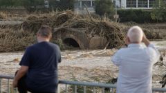 Varios ciudadanos contemplan el estado de un puente cado en el municipio e Ribarroja del Turia.