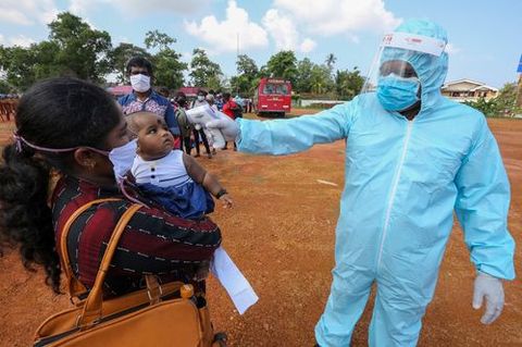 Un hombre toma la temperatura a los que suben al autob�s en Sri lanka