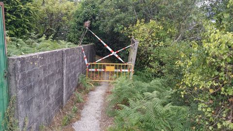 Vallado de seguridad y carteler�a de advertencia en el acceso a la playa de A Xurela, en Paderne. 