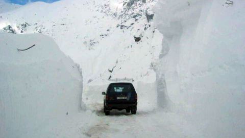 Un coche circula rodeado de grandes monta�as de nieve en San Isidro