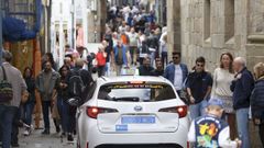 Un taxi abrindose camino por la ra do Franco, repleta de turistas