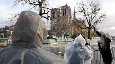 Turistas protegidos con chuvasqueros tratan de fotografiar la catedral desde la distancia