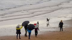 Paseantes por la playa de San Lorenzo, en Gij�n, en un d�a de lluvia