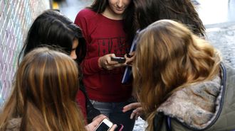 Estudiantes usando el tel�fono m�vil a la salida del colegio.