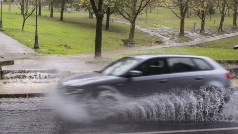 Un coche circula en medio de una lluvia intensa.