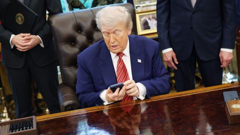 Donald Trump comprueba su teléfono móvil en el Despacho Oval de la Casa Blanca