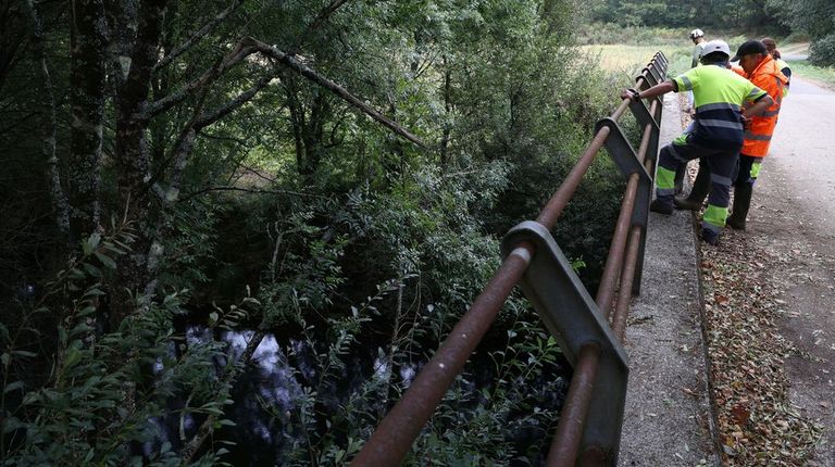 Trabajadores en la tarde del martes junto al cauce fluvial afectado, que desprende fuerte olor a pur&iacute;n