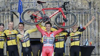 Primoz Roglic, ganador de la Vuelta del 2021, levanta su bicicleta tras proclamarse campe&oacute;n en la Praza do Obradoiro.
