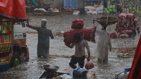 Vecinos de Lahore (Pakistn) ponen a salvo algunas mercancas por las lluvias del monzn.