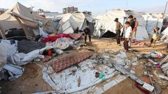 Un grupo de jvenes y nios palestinos observan los daos causados por un bombardeo israel en un campamento de desplazado en Jan Yunis, en el sur de la Franja