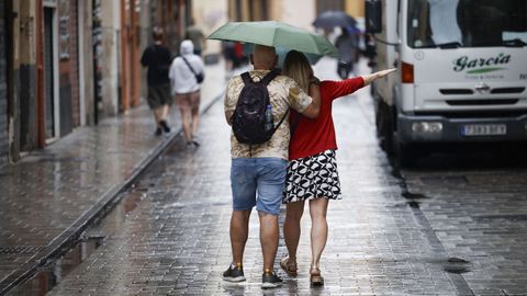 Dos personas se protegen de la lluvia en Valencia.