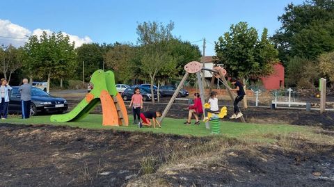 Unos nios, en el parque infantil del Rosende (Sober), rodeados de terreno quemado