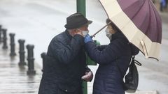 Gente mayor paseando bajo la lluvia en Santiago