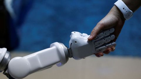 Charlermpon Punnotock, director general de CT Asia Rob�tica da una mano a un robot en Bangkok (Tailandia)