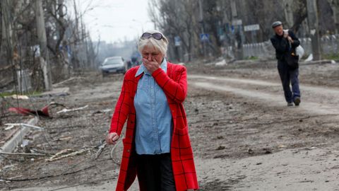 Una mujer se emociona en una calle de Maripol donde quedan a la vista los destrozos 