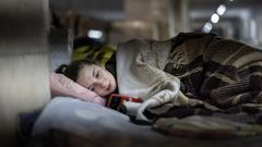 Una joven consulta su tel�fono m�vil en un refugio de Kiev