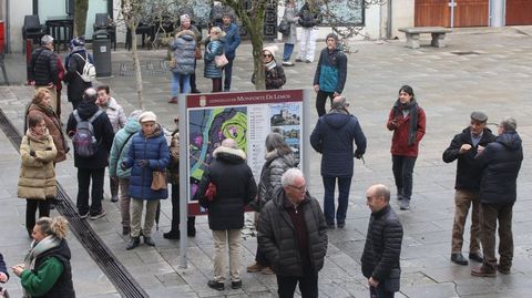 Integrantes de una excursin en grupo hacen tiempo en Monforte junto a un indicador con informacin turstica