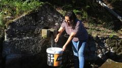 Susana P�rez recogiendo un cubo de agua en una fuente pr�xima a su vivienda