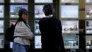 Unos viandantes consultan las ofertas en el escaparata de una inmobilaria