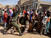 Un soldado dispersa a una multitud de saqueadores.